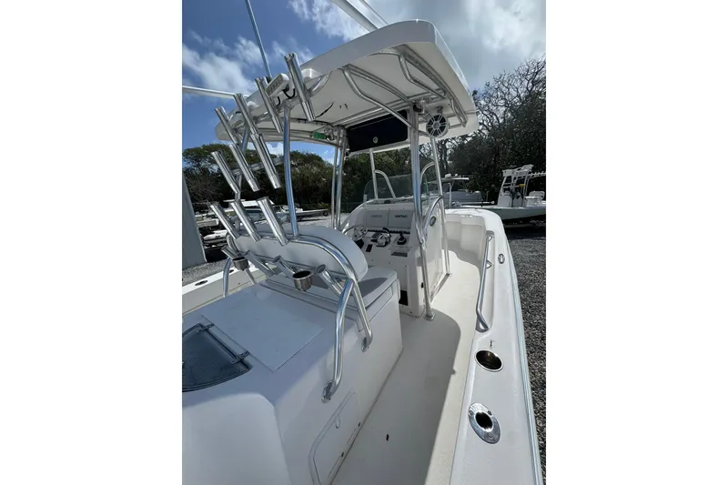 Slide: The Image of 2019 Twin Vee 26 Center Console boat with T-top and rod holders, docked outdoors. - 2