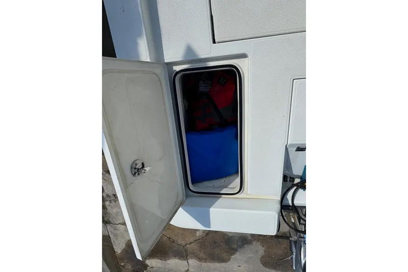 Slide: The Image of Open storage compartment on 2011 Ranger 2400 Bay Ranger boat, containing life jackets. - 15