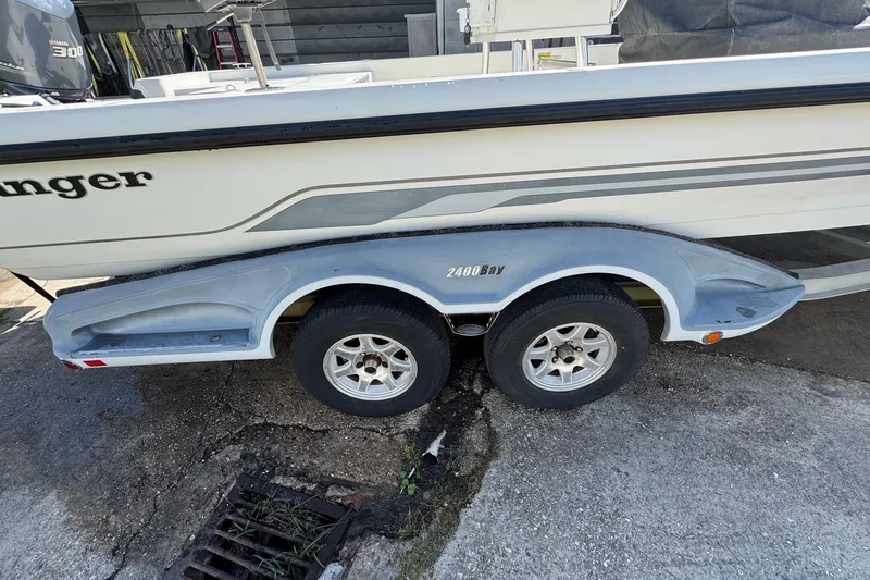 Slide: The Image of 2011 Ranger 2400 Bay boat on trailer, side view showing wheels and hull design. - 5