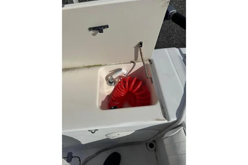 Slide: The Image of Storage compartment with red coiled hose on 2000 Sport-Craft 241 Walk Around boat. - 11