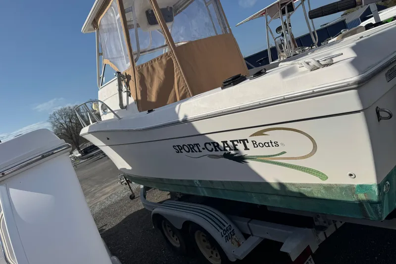 Slide: The Image of 2000 Sport-Craft 241 Walk Around boat on trailer, side view with logo visible. - 2