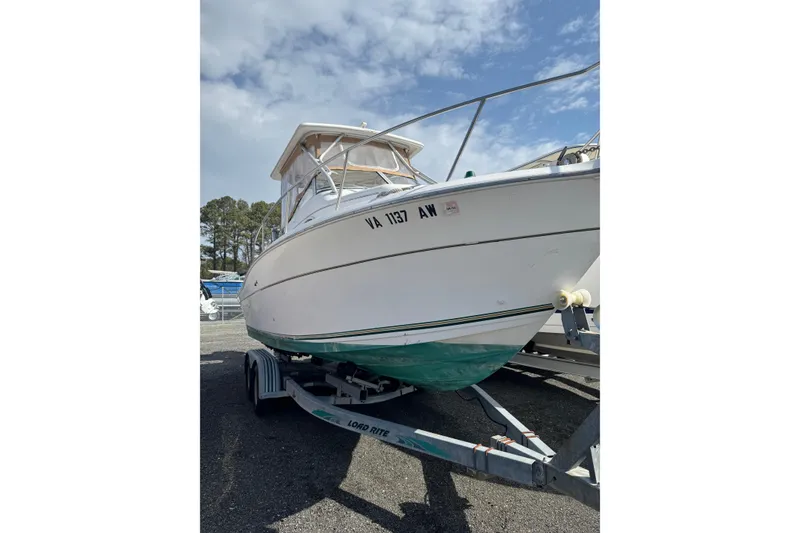 Slide: The Image of 2000 Sport-Craft 241 Walk Around boat on trailer under a partly cloudy sky. - 4