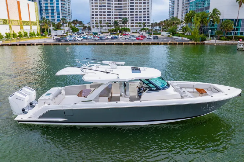 The Image of 2024 Tiara Yachts 43 LS luxury boat docked in a marina with modern buildings. - 1