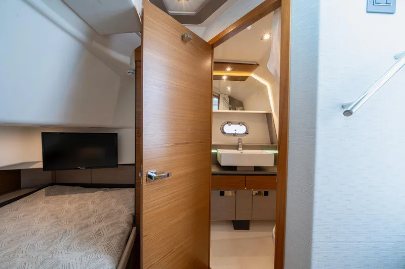 Slide: The Image of 2024 Tiara Yachts 43 LS interior cabin with bed, TV, and modern bathroom. - 11