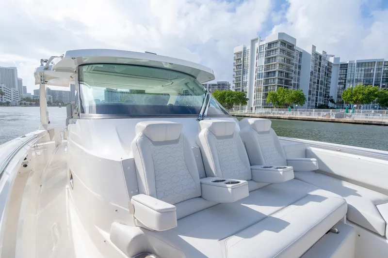 Slide: The Image of 2024 Tiara Yachts 43 LS luxury yacht with plush seating, docked near modern buildings. - 22