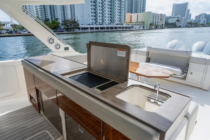 Slide: The Image of 2024 Tiara Yachts 43 LS yacht deck with grill and sink, overlooking waterfront cityscape. - 32