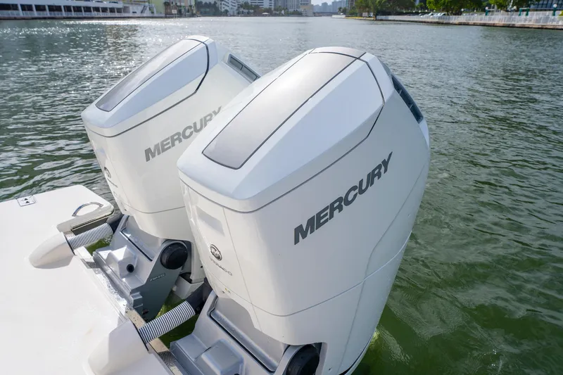 Slide: The Image of Twin Mercury outboard engines on a 2024 Tiara Yachts 43 LS, docked on calm water. - 49