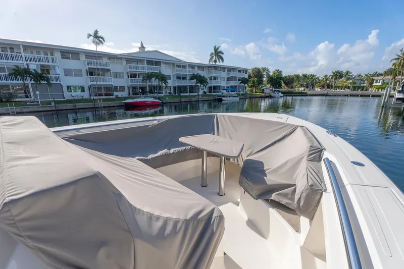 Slide: The Image of 2024 Tiara Yachts 43 LS boat with covered seating area, docked near waterfront buildings. - 50