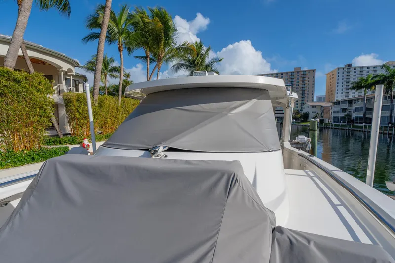 Slide: The Image of 2024 Tiara Yachts 43 LS docked, covered, with palm trees and waterfront buildings in the background. - 51