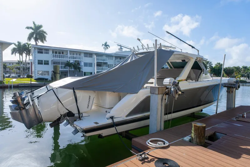 Slide: The Image of 2024 Tiara Yachts 43 LS docked, covered, with Mercury outboard engines, in a sunny marina setting. - 57