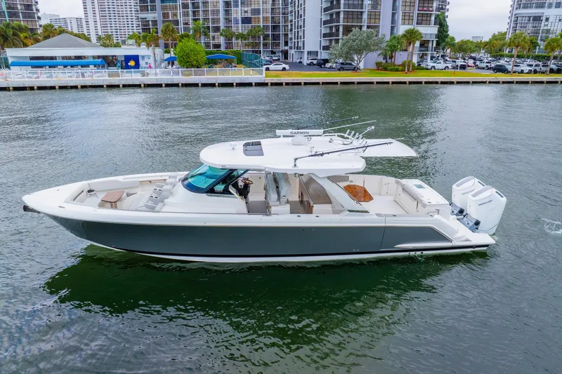 Slide: The Image of 2024 Tiara Yachts 43 LS cruising on a calm waterway near modern buildings. - 7