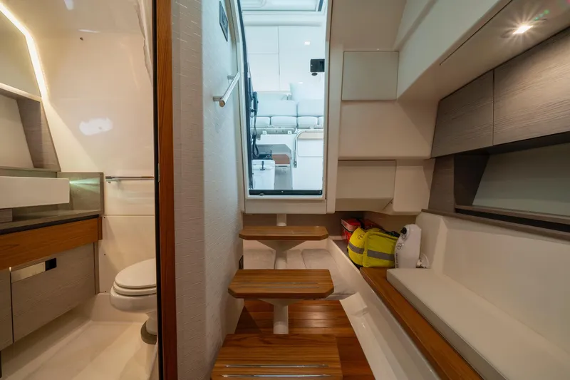 Slide: The Image of 2024 Tiara Yachts 43 LS interior with wooden steps, seating, and compact bathroom. - 9