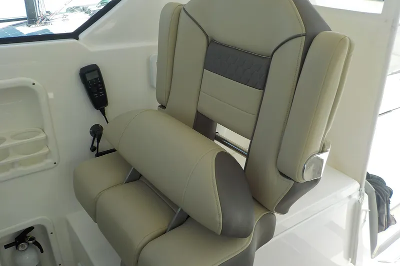 Slide: The Image of Captain's chair on 2020 Pursuit OS 355 Offshore boat, featuring beige and gray upholstery. - 10