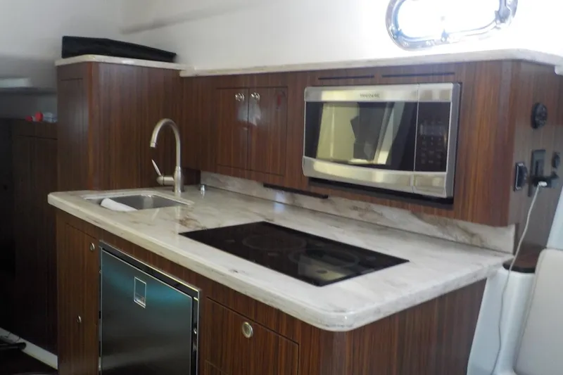 Slide: The Image of 2020 Pursuit OS 355 Offshore yacht kitchen with modern appliances and wood cabinetry. - 18