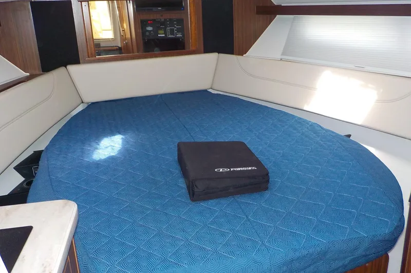 Slide: The Image of 2020 Pursuit OS 355 Offshore cabin interior with blue bedding and seating area. - 19