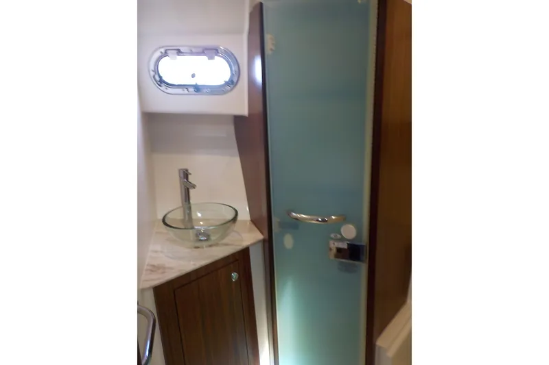 Slide: The Image of 2020 Pursuit OS 355 Offshore bathroom with glass sink and frosted shower door. - 22