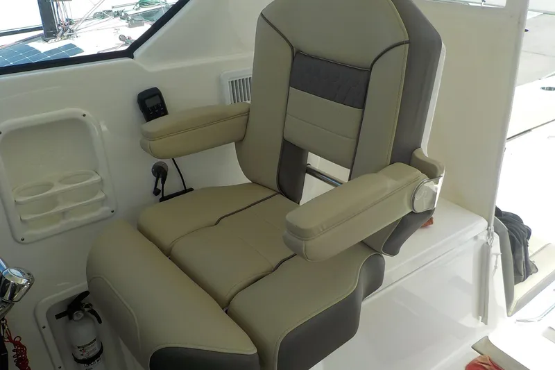 Slide: The Image of Captain's chair on 2020 Pursuit OS 355 Offshore boat, featuring beige and gray upholstery. - 9