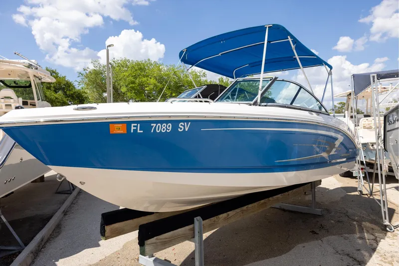 Slide: The Image of 2021 Chaparral 21 SSi OB boat with blue hull and canopy, displayed outdoors. - 1