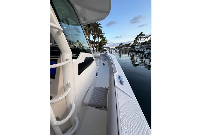 Slide: The Image of 2023 Boston Whaler 380 Outrage boat docked by palm-lined waterfront. - 10