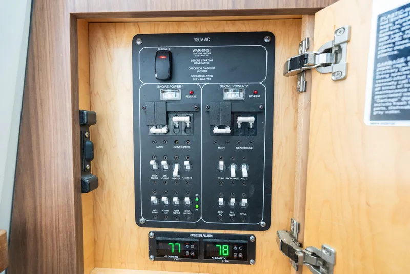 Slide: The Image of Electrical control panel inside a 2020 Boston Whaler 380 Outrage boat, featuring various switches and indicators. - 42