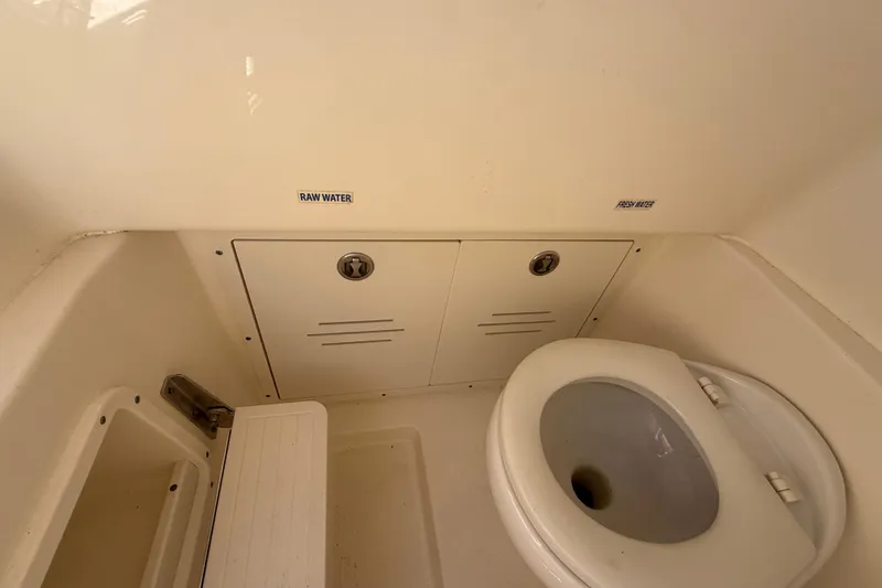 Slide: The Image of 2019 Key West Billistic 281 Center Console boat bathroom interior with toilet and storage compartments. - 107