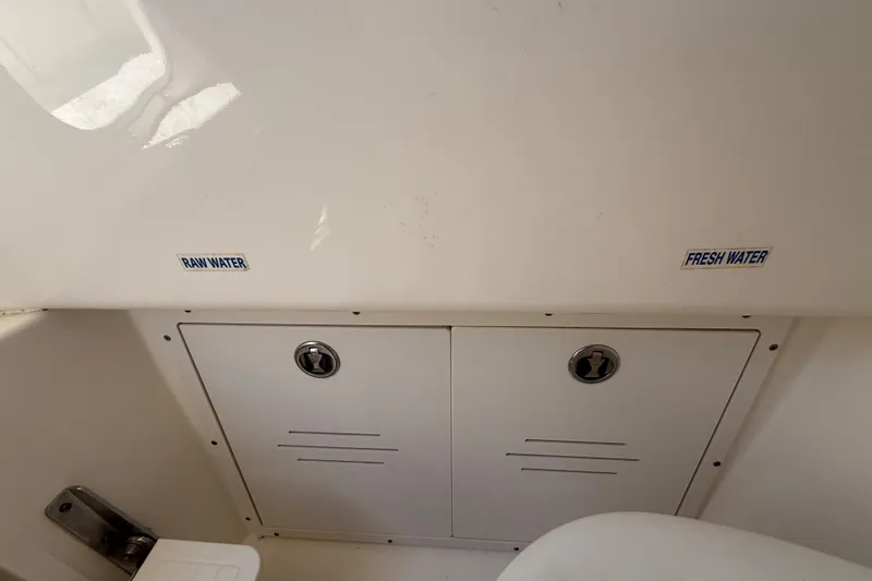 Slide: The Image of 2019 Key West Billistic 281 Center Console water access panel with raw and fresh water labels. - 115