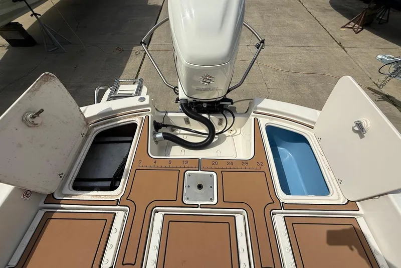 Slide: The Image of 2020 Carolina Skiff 26 Ultra Elite boat deck with storage compartments and Suzuki outboard motor. - 16