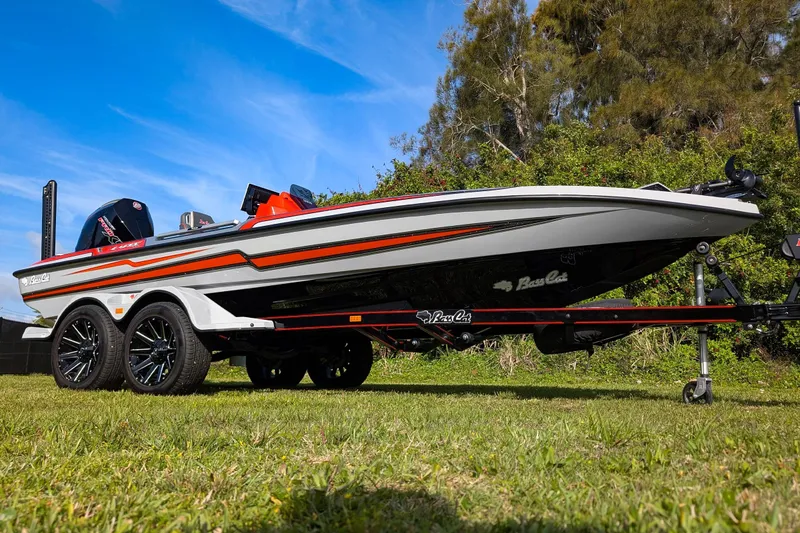 Slide: The Image of 2026 Bass Cat Lynx STS boat on trailer, parked on grass under blue sky. - 12