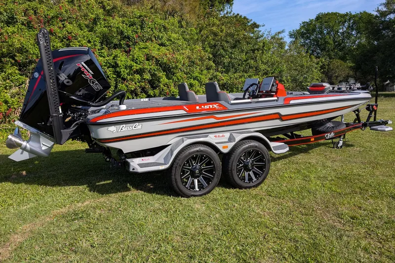 Slide: The Image of 2026 Bass Cat Lynx STS boat on trailer, parked on grass, with vibrant design. - 15
