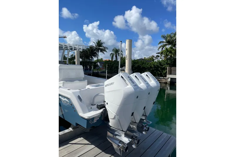 Slide: The Image of 2024 Invincible 36 Open Fisherman with triple Mercury engines docked by palm trees. - 2