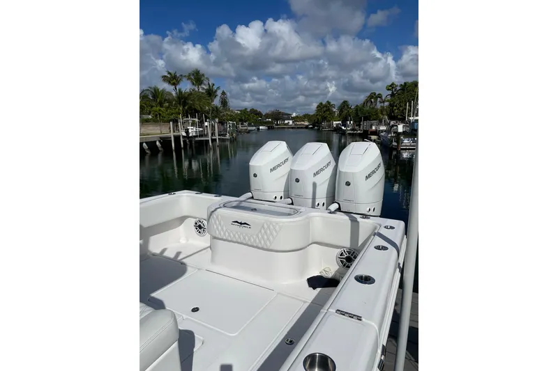 Slide: The Image of 2024 Invincible 36 Open Fisherman boat with triple Mercury engines docked by a serene waterfront. - 4