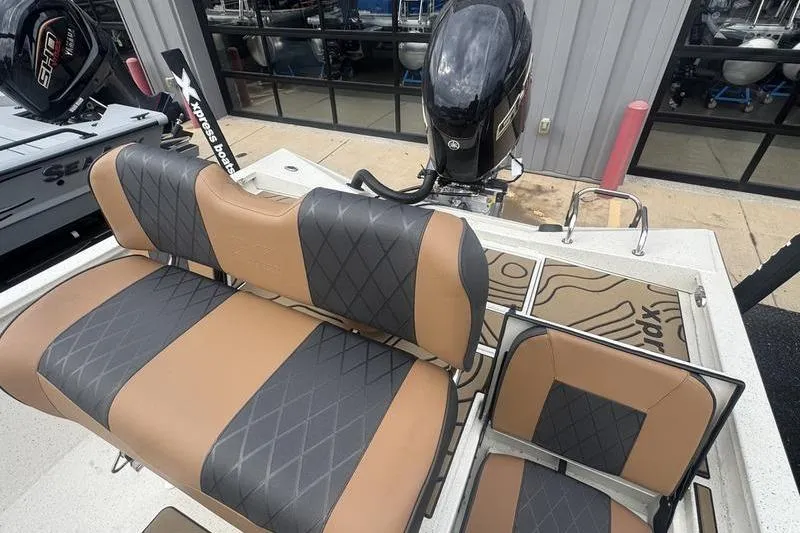 Slide: The Image of 2026 Xpress H22 boat interior with brown and black diamond-stitched seats, outboard motor visible. - 23