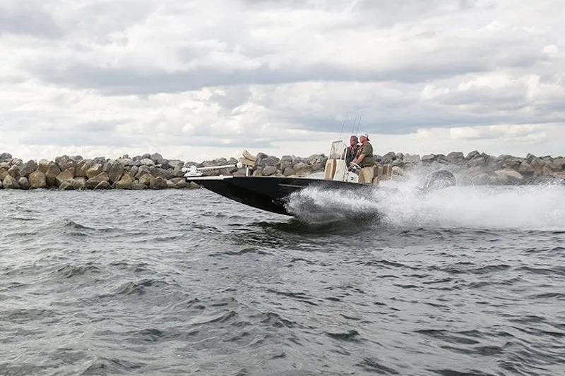 Slide: The Image of 2026 Xpress H22 boat speeding on water near rocky shoreline under cloudy sky. - 5
