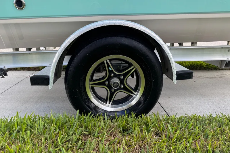 Slide: The Image of Trailer wheel of 2022 Carolina Skiff 19 LS boat on grass and pavement. - 16