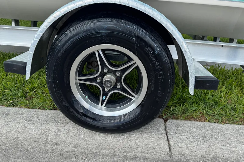 Slide: The Image of Trailer wheel of a 2022 Carolina Skiff 19 LS boat on grass. - 22
