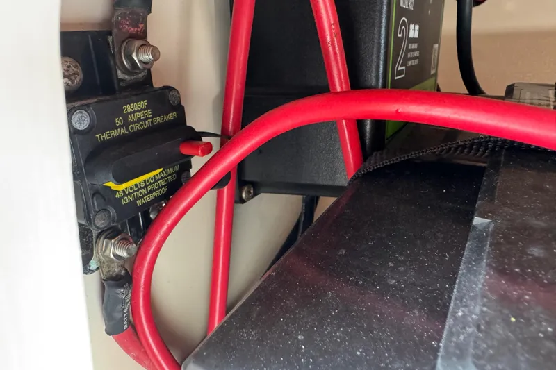 Slide: The Image of Close-up of a 50-amp thermal circuit breaker with red cables in a 2022 Carolina Skiff 19 LS. - 60