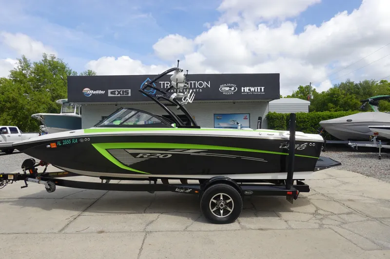 The Image of 2015 Tigé R20 boat with green accents on a trailer, parked outside a dealership. - 1