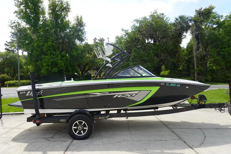 Slide: The Image of 2015 Tigé R20 boat with green accents on a trailer, parked outdoors. - 4
