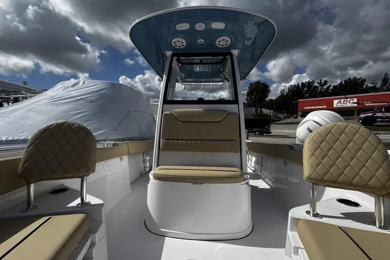 Slide: The Image of 2026 Sportsman Heritage 231 Center Console boat interior with cushioned seating under cloudy sky. - 10