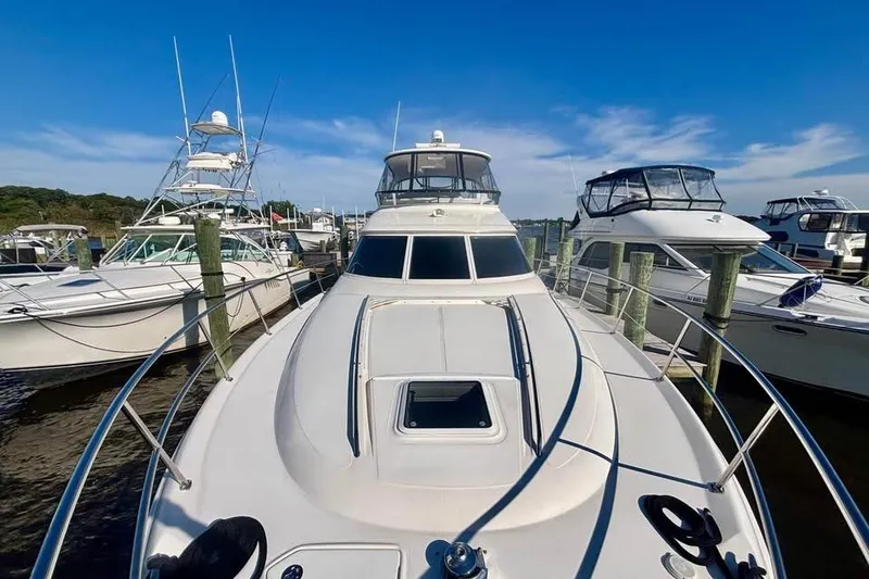 Slide: The Image of 2003 Sea Ray 480 Sedan Bridge yacht docked among other boats under a clear blue sky. - 5