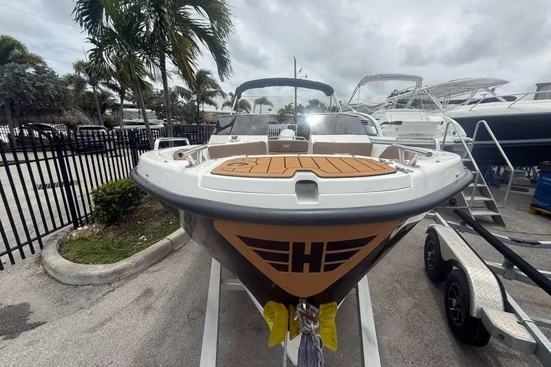 Slide: The Image of Front view of a 2025 Drive Wave 570 boat on a trailer, surrounded by palm trees. - 19