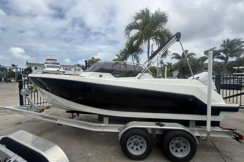 The Image of 2025 Drive Wave 570 boat on trailer, parked outdoors with palm trees in the background. - 1