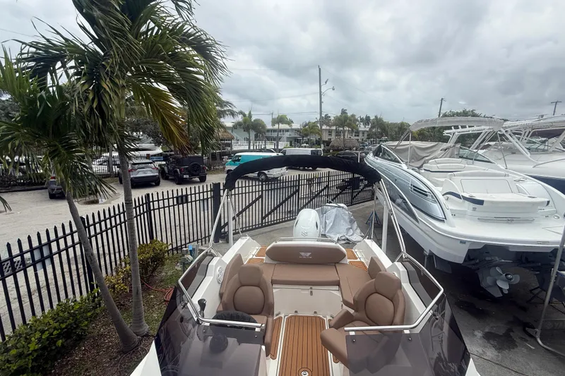 Slide: The Image of 2025 Drive Wave 570 boat docked, surrounded by palm trees and other boats under cloudy skies. - 13