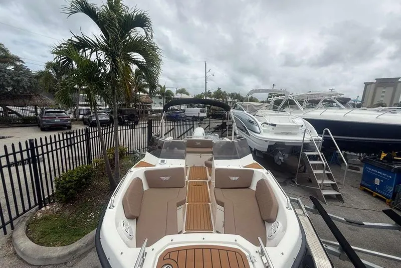 Slide: The Image of 2025 Drive Wave 570 boat with sleek design, docked near palm trees and other vessels. - 18