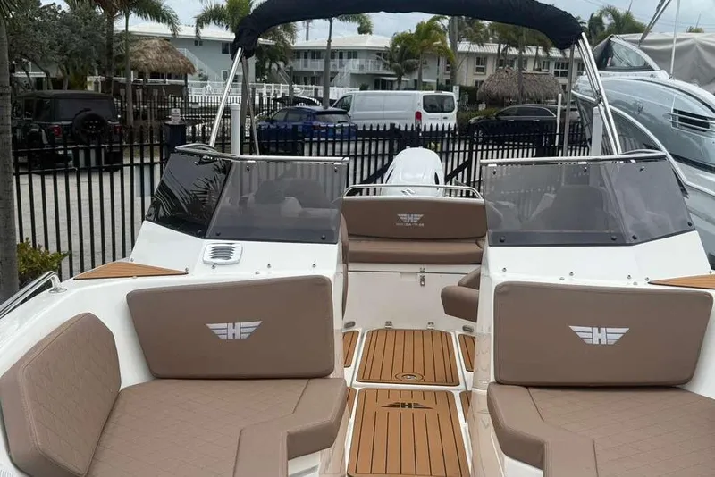 Slide: The Image of 2025 Drive Wave 570 boat interior with tan seating and wood accents, docked outdoors. - 20