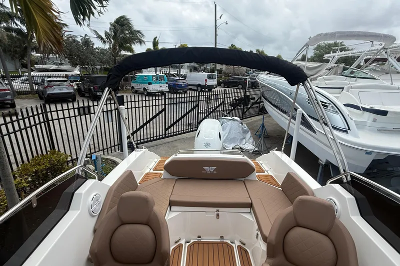 Slide: The Image of 2025 Drive Wave 570 boat interior with tan seating, docked near other boats. - 9