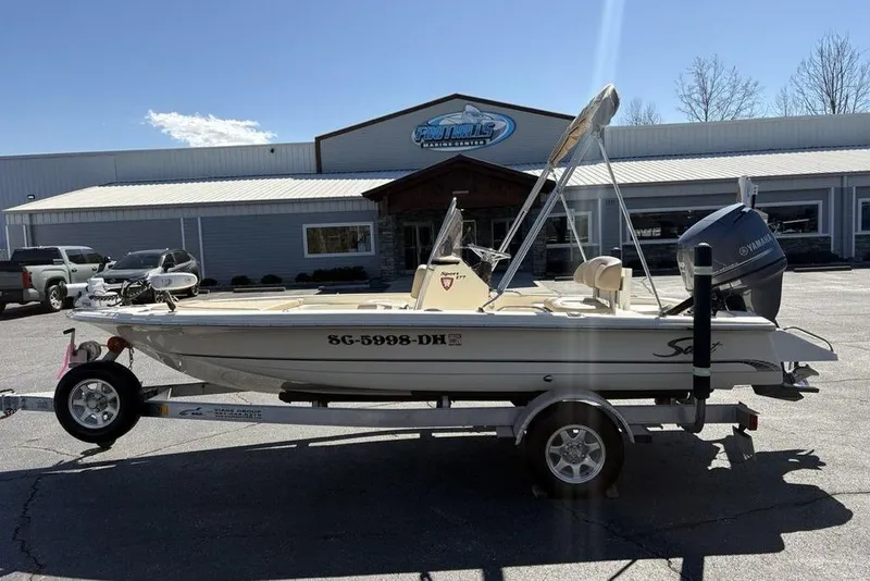 The Image of 2016 Scout 177 Sport boat on trailer, parked outside a dealership under clear skies. - 1