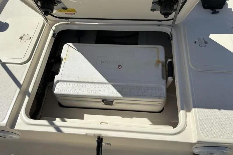 Slide: The Image of Open storage compartment on a 2016 Scout 177 Sport boat with a cooler inside. - 20