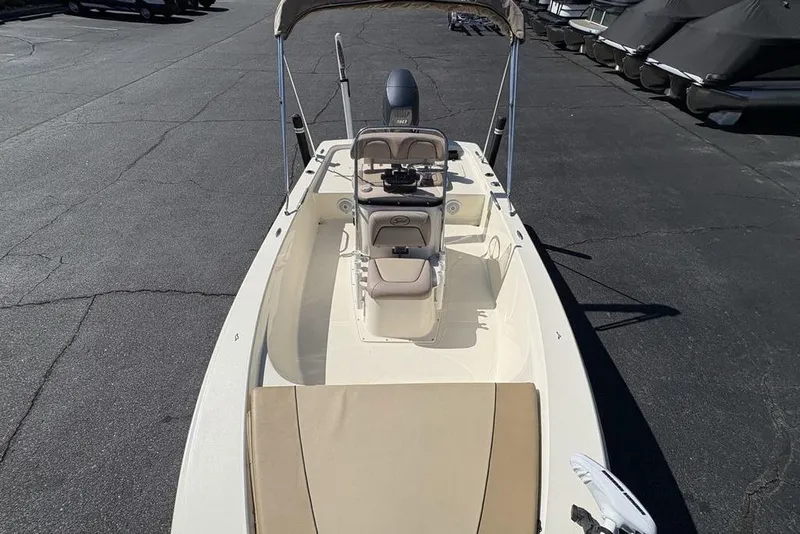 Slide: The Image of 2016 Scout 177 Sport boat with beige seating and canopy, parked on asphalt. - 24