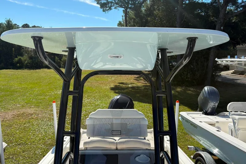 Slide: The Image of 2026 Key West 230 Bay Reef boat with T-top and seating, parked outdoors. - 4